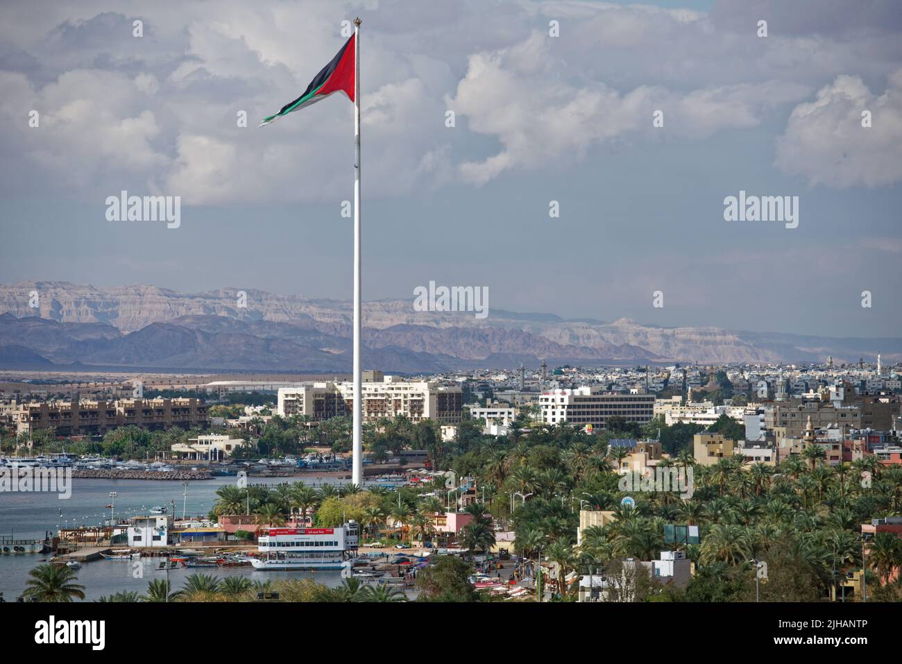 Bandiera nazionale che sventola sul porto di Aquaba, Giordania, contro un paesaggio urbano Foto Stock