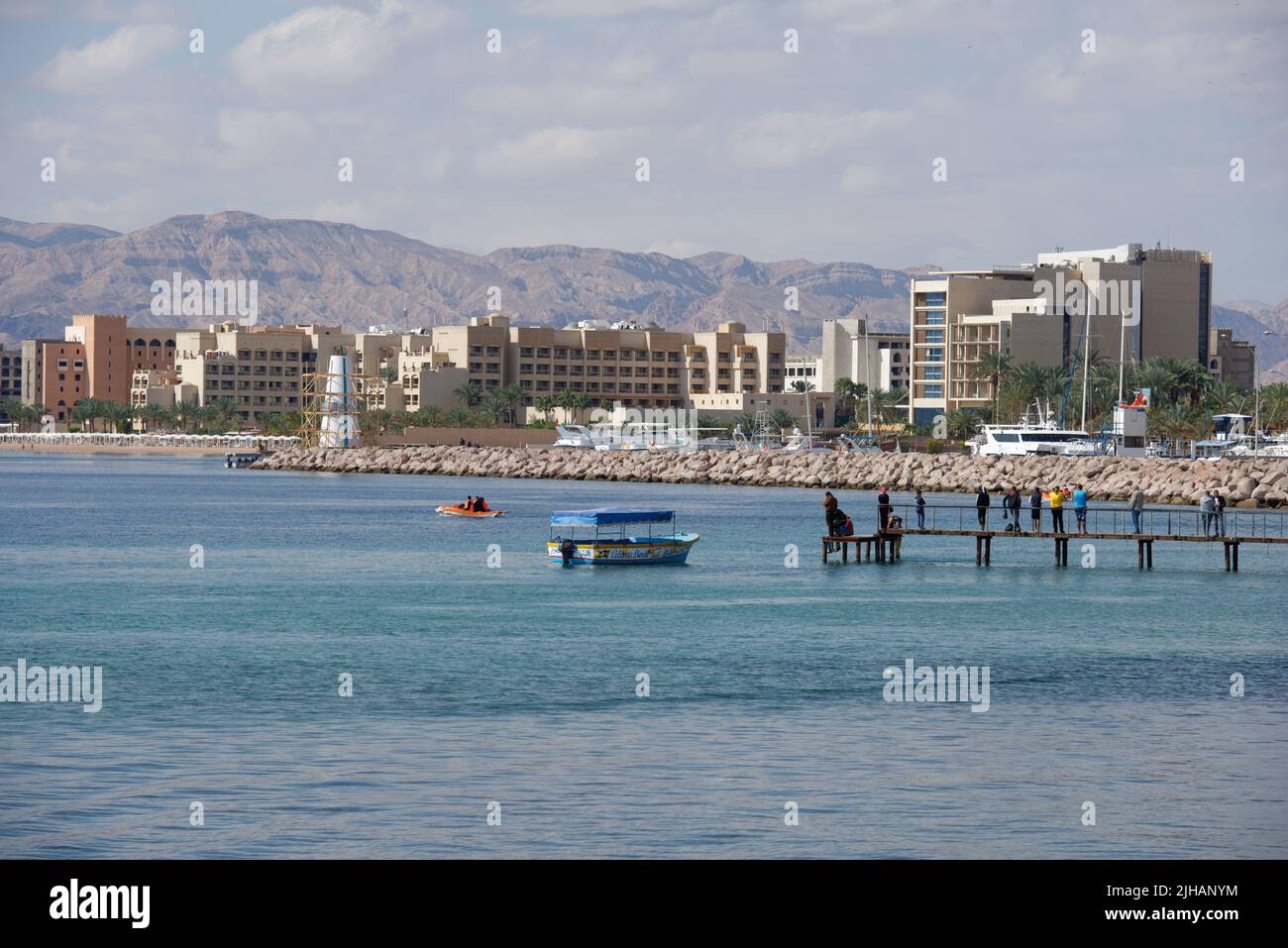 Aqaba, Giordania - 14 marzo 2014: Persone sul molo contro il porto turistico e nuovi hotel di North Beach Foto Stock