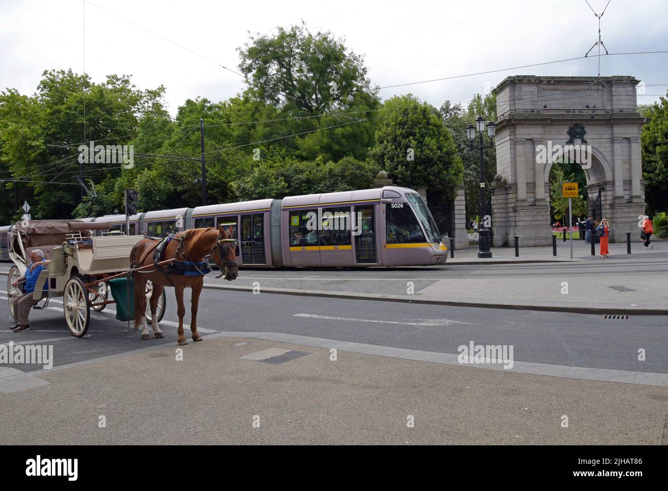 Carrozza trainata da cavalli e tram LUAS di fronte all'Arco di Fusiliers, St Stephen's Green, Dublino, Irlanda, luglio 2022 Foto Stock