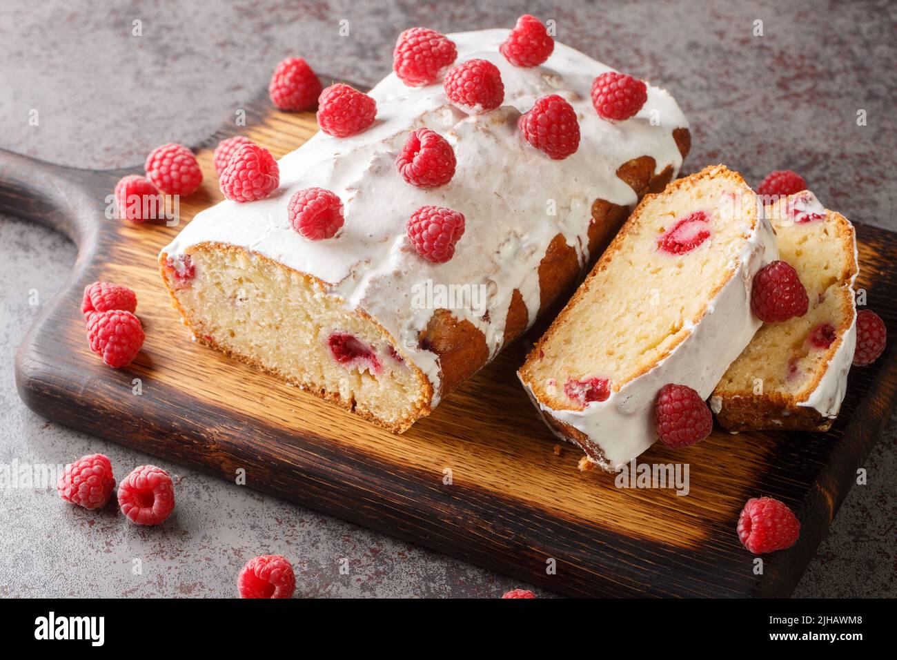 Torta alla vaniglia con lampone e glassa di limone bianco primo piano su un asse di legno sul tavolo. Orizzontale Foto Stock