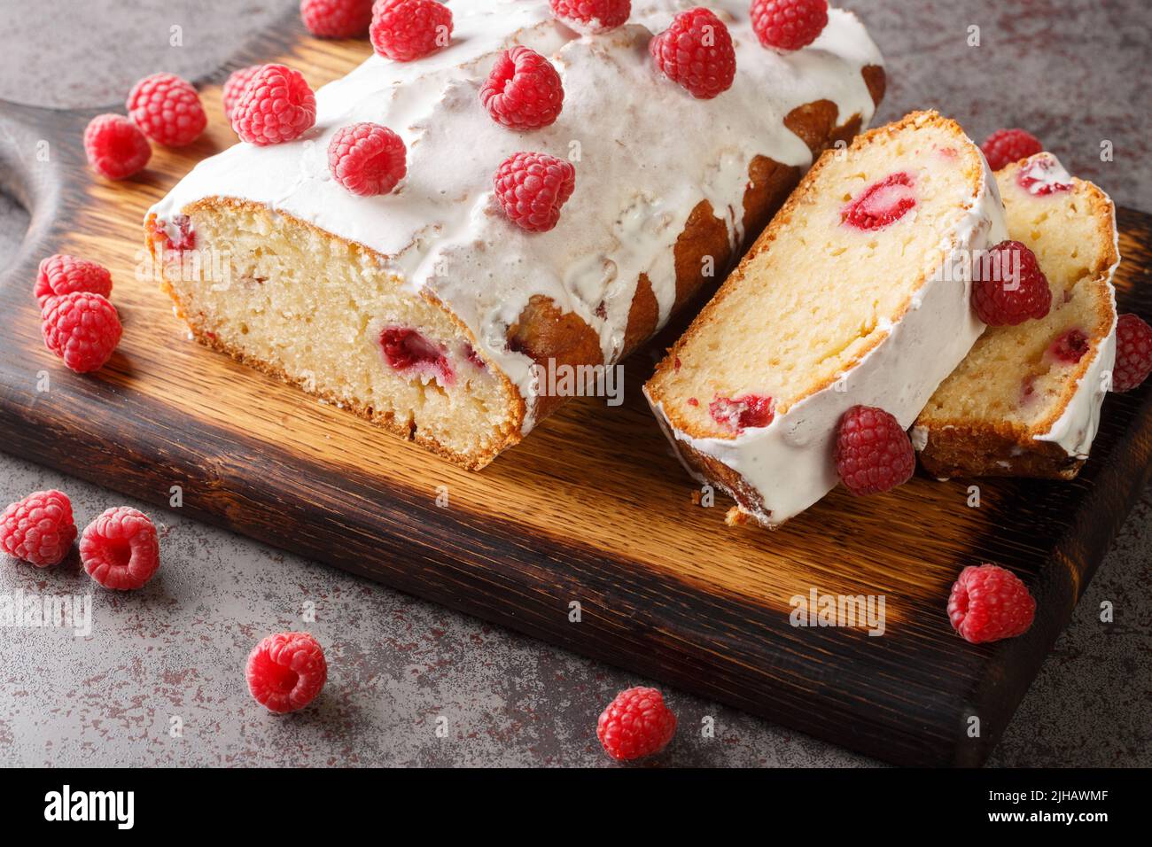 Delizioso pane per torte al lampone con glassa al limone da vicino su un asse di legno sul tavolo. Orizzontale Foto Stock