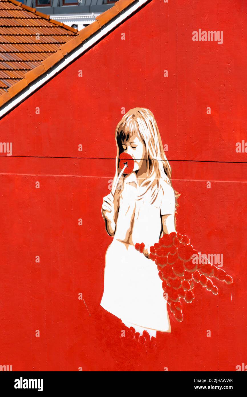 Graffiti di ragazza che puzzano un fiore sul lato di una casa rossa brillante. Stavanger, Norvegia Foto Stock