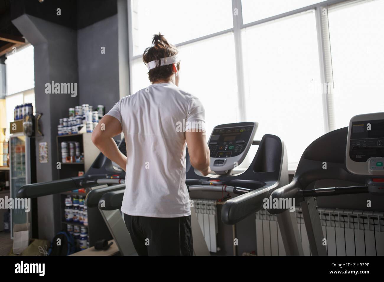Scatto posteriore di un atleta maschio che si allena in palestra, che corre sul tapis roulant Foto Stock