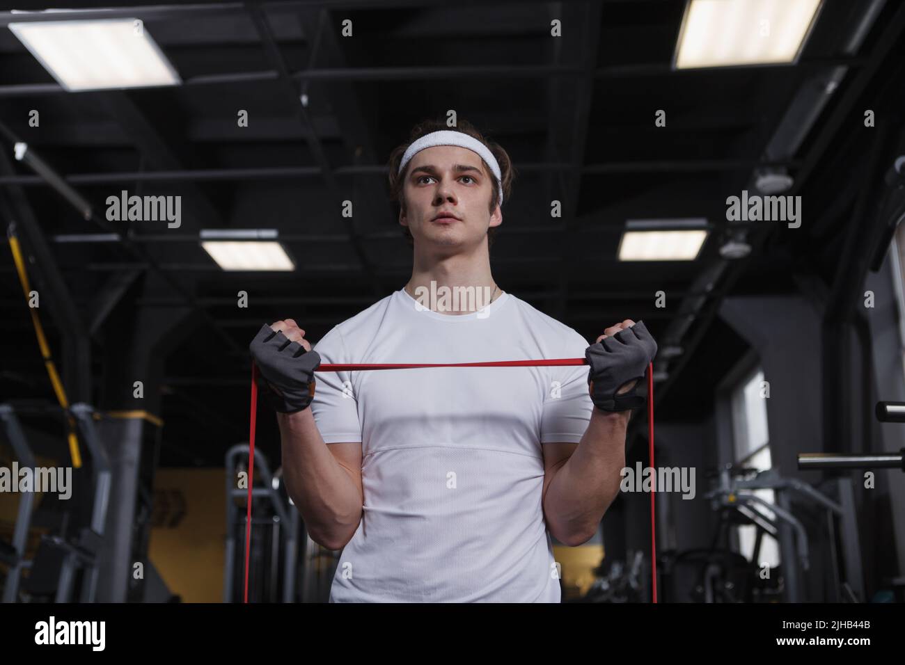 Scatto ad angolo basso di uno sportivo che fa un allenamento bicipite, utilizzando la banda di resistenza Foto Stock