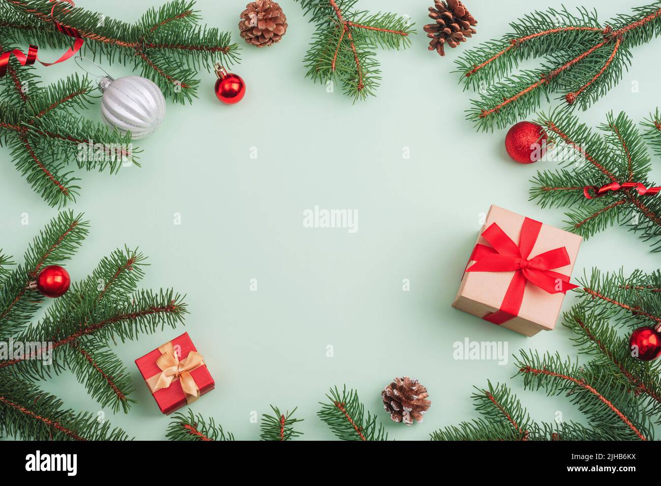 Decorazioni natalizie, scatole regalo, rami di abete, baubles e coni di pino su sfondo verde chiaro. Vista dall'alto, disposizione piatta, spazio di copia. Foto Stock