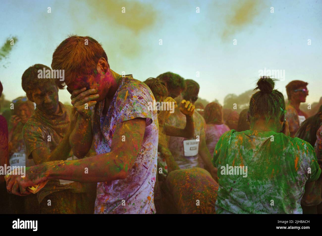 La gente protegge i propri occhi mentre la polvere più colorata erutta nell'aria intorno a loro al Color Walk di Dubai, Emirati Arabi Uniti. Il divertimento è pericoloso. Foto Stock