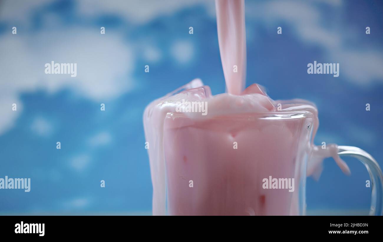 Primo piano tazza di vetro doppia con movimento versante di colore rosa pastello bevanda con sfondo cielo blu, tema pastello, movimento sfocato Foto Stock