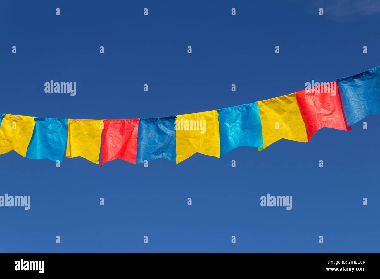 Goiania, Goiás, Brasile – 17 luglio 2022: Un clothesline con pennants tessuto contro il cielo blu per festa di giugno - tipico festival brasiliano. Quadrilha Foto Stock