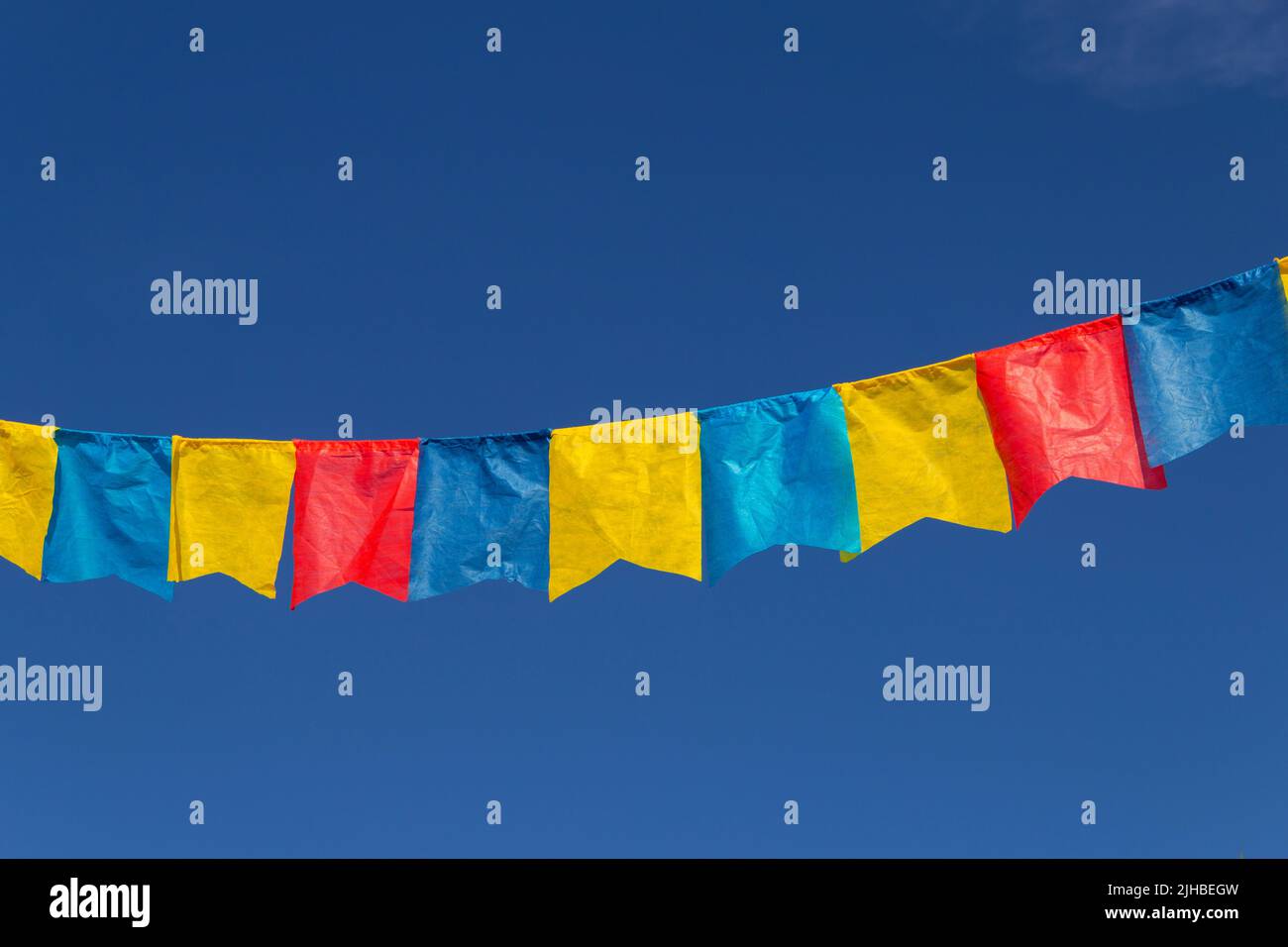 Goiania, Goiás, Brasile – 17 luglio 2022: Un clothesline con pennants tessuto contro il cielo blu per festa di giugno - tipico festival brasiliano. Quadrilha Foto Stock