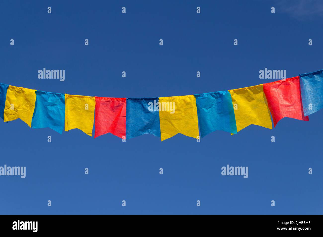 Goiania, Goiás, Brasile – 17 luglio 2022: Un clothesline con pennants tessuto contro il cielo blu per festa di giugno - tipico festival brasiliano. Quadrilha Foto Stock