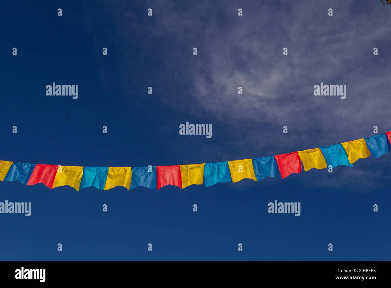 Goiania, Goiás, Brasile – 17 luglio 2022: Un clothesline con pennants tessuto contro il cielo blu per festa di giugno - tipico festival brasiliano. Quadrilha Foto Stock