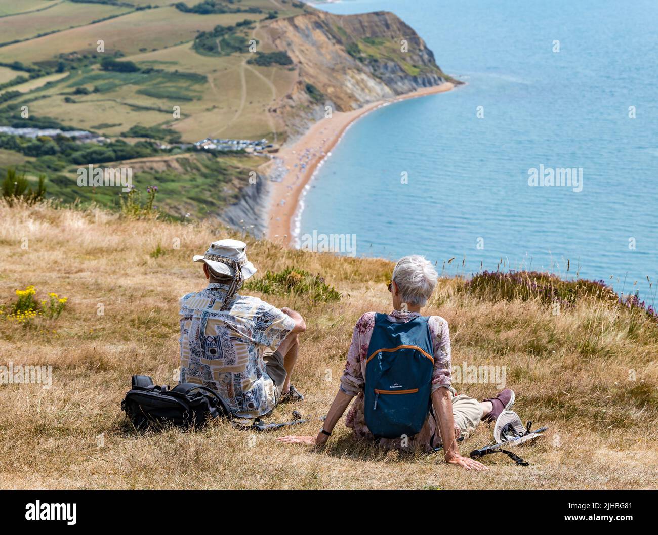 Dorset, Inghilterra, Regno Unito, 17th luglio 2022. UK Meteo: Onda di calore marina. Una giornata molto calda lungo il sentiero costiero reso sopportabile da una brezza marina. Una vista sulla spiaggia di Seatown con una coppia anziana che riposa e ammira la vista sulla cima della scogliera di Golden Cap. L'uomo ha compiuto 90 anni la settimana scorsa e sua moglie ha 80 anni Foto Stock