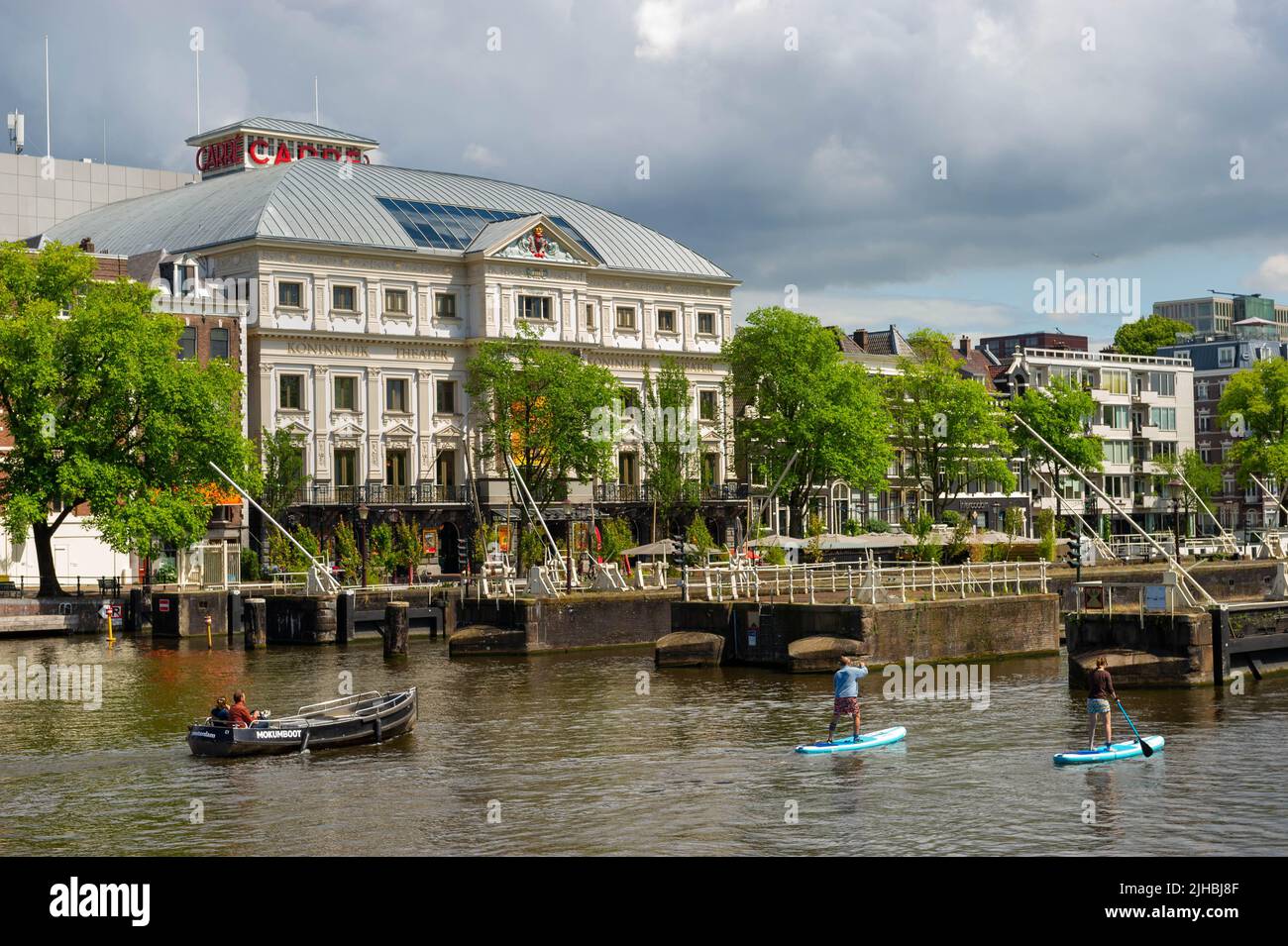 Barche che passano attraverso le chiuse di Amstel (Amstelsluizen) Amsterdam in una giornata di sole con il Teatro reale Carre sullo sfondo Foto Stock