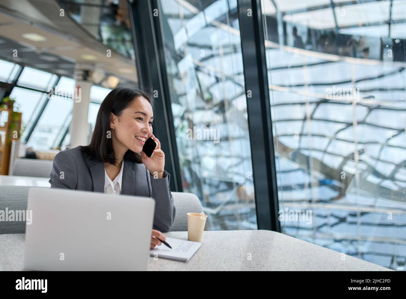 Giovane donna asiatica felice di affari che indossa il vestito che parla al telefono in ufficio. Foto Stock