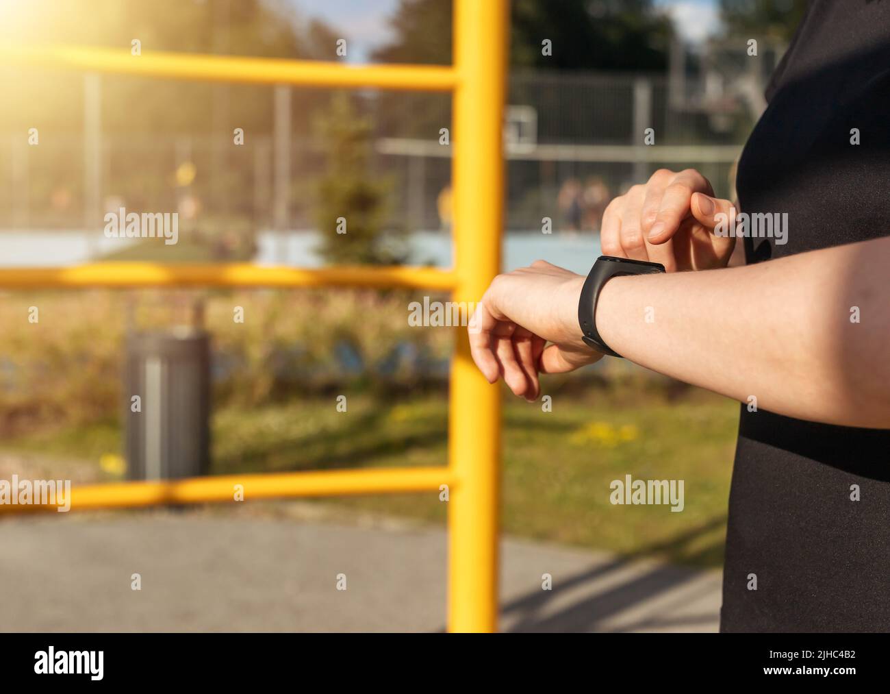 Donna che utilizza il tracker di fitness per il monitoraggio del numero di passi o della frequenza cardiaca durante l'esercizio allo stadio. Monitoraggio delle attività fisiche mediante dispositivo elettronico. Foto di alta qualità Foto Stock