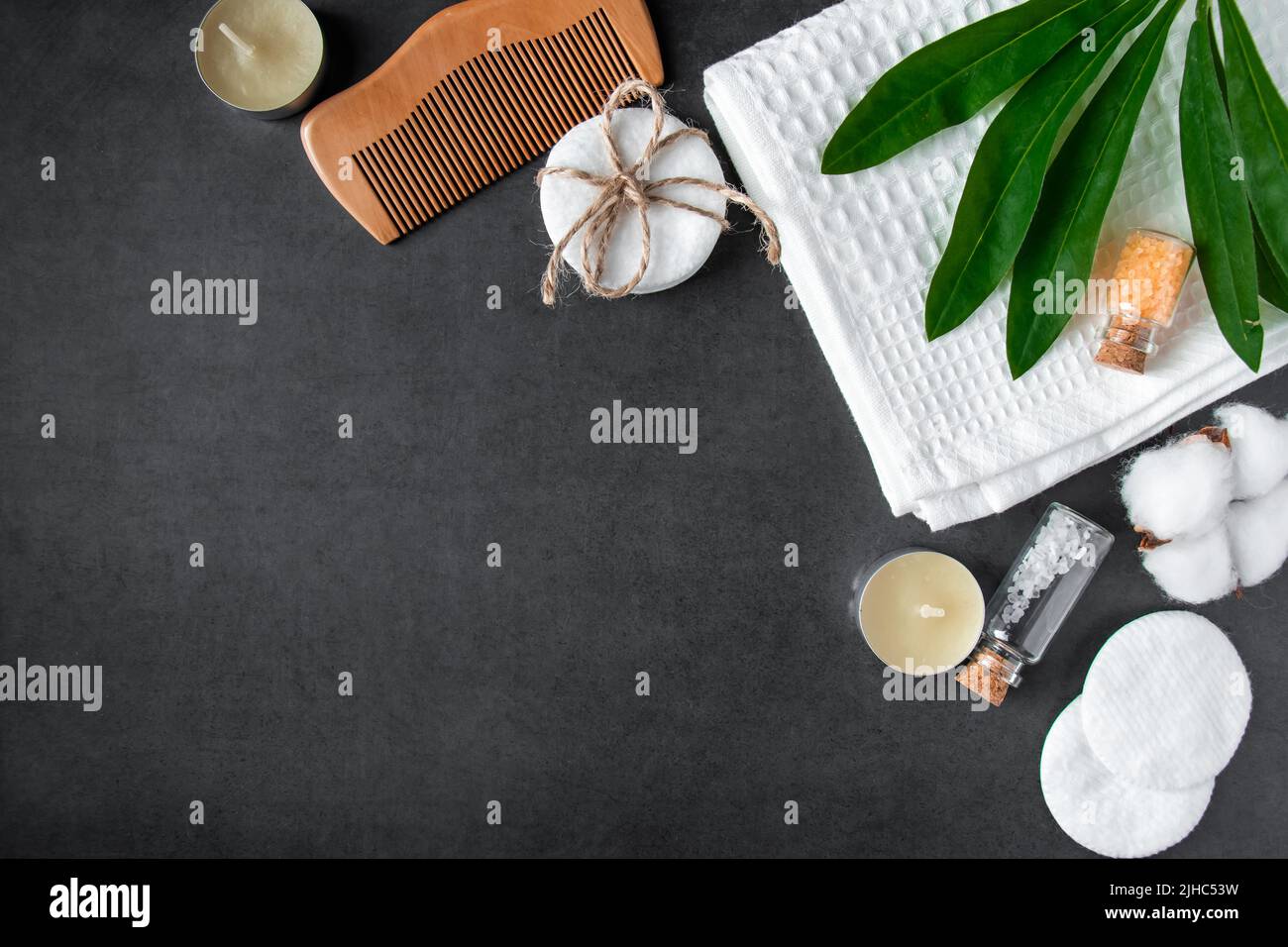 Cosmetici naturali per la cura del corpo su sfondo concreto. Accessori per il centro benessere, asciugamano, spazzola per capelli, olio essenziale. Composizione della disposizione piatta. Prodotti ecologici, Zer Foto Stock