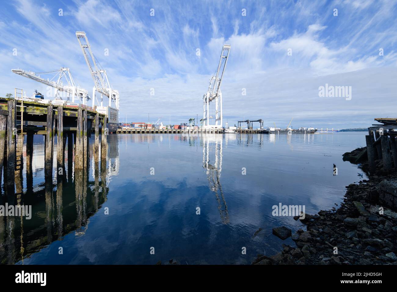 Seattle - 09 luglio 2022; ampia vista delle gru del porto di Seattle e di un vecchio molo di legno sotto il cielo blu con strisce di nubi Foto Stock