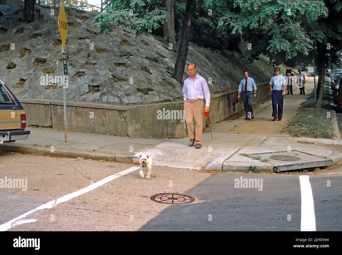 WASHINGTON DC - AGOSTO 1989 Felix Bloch (pantaloni tan con camicia bianca) ex direttore degli affari europei e canadesi per il Dipartimento di Stato degli Stati Uniti, collegato al caso spia Robert Hanssen (agente FBI), Cammina il suo cane lungo Bancroft St NW nella sezione Embassy Row di Washington.He è seguito da due agenti maschi FBI, ma non è mai stato accusato di alcun crimine. Foto Stock