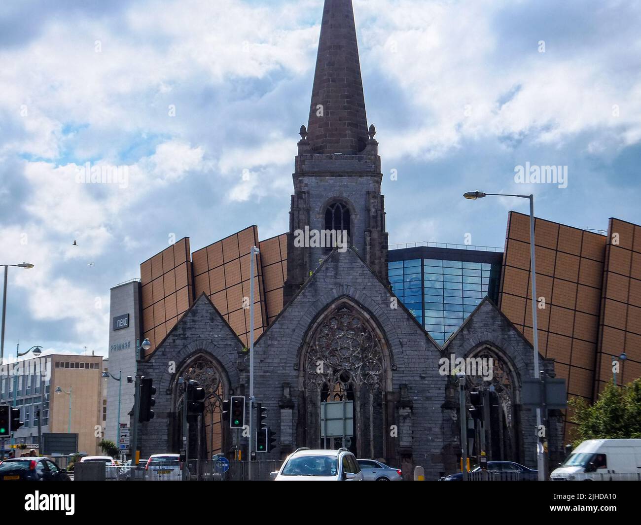 Il moderno centro commerciale Drake Circus sorge in contrasto dietro le rovine della chiesa di Charles del 17th secolo a Plymouth, Devon, Inghilterra, Regno Unito. Foto Stock