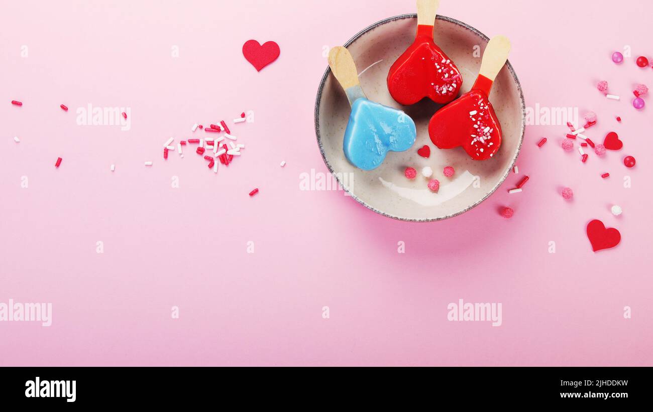 Diversi tipi di gelato a forma di popsicle su sfondo rosa. Atmosfera estiva. Vista dall'alto, disposizione piatta, spazio di copia Foto Stock