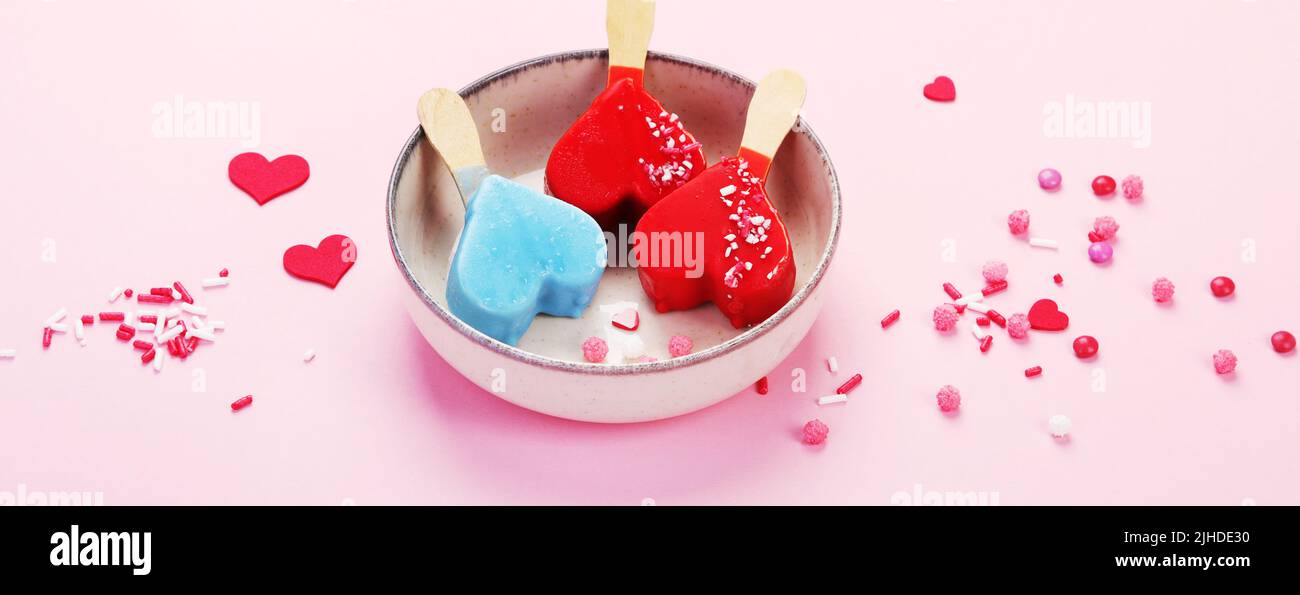Diversi tipi di gelato a forma di popsicle su sfondo rosa. Atmosfera estiva. Panorama Foto Stock