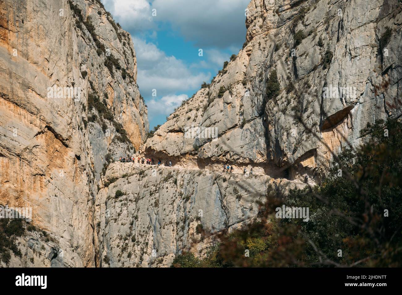 Spettacolare scogliera con una passerella all'interno della roccia con persone che fanno escursioni. Congost de Mont Rebei, Catalogna, Spagna. Foto Stock