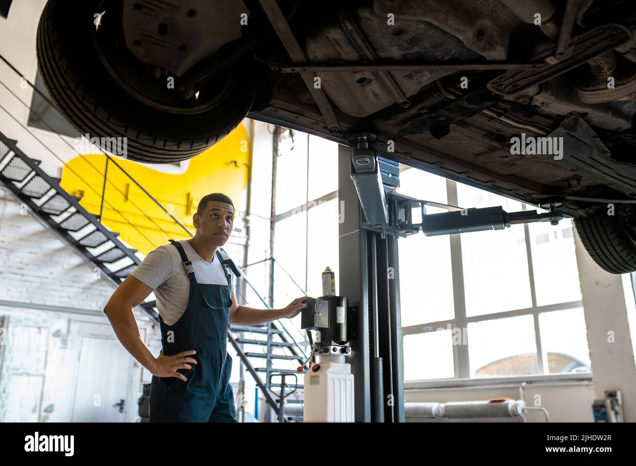 Tecnici al servizio auto che fanno l'ascensore per l'ispezione dell'auto Foto Stock