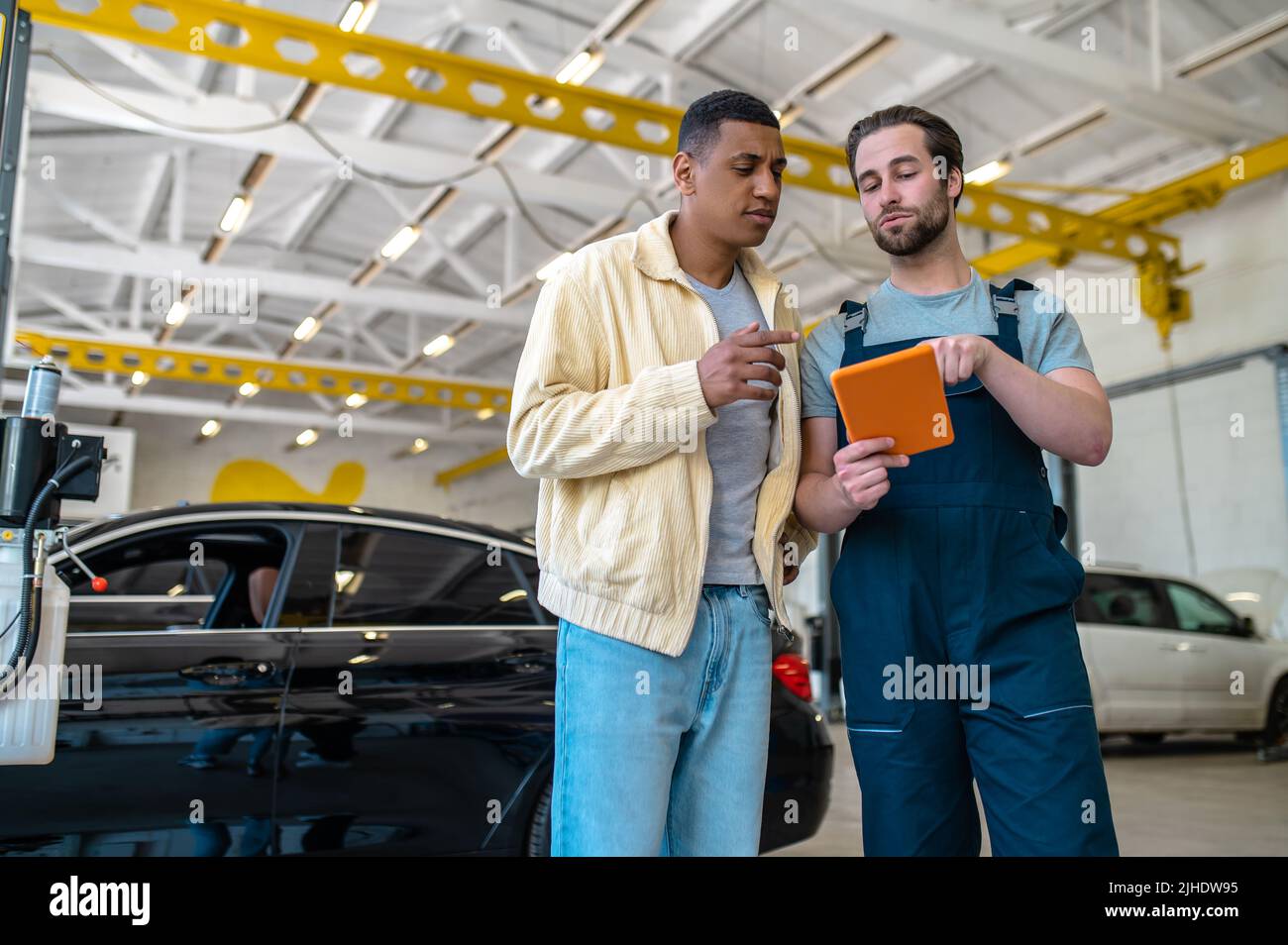 Due uomini che parlano guardando lo schermo del tablet Foto Stock
