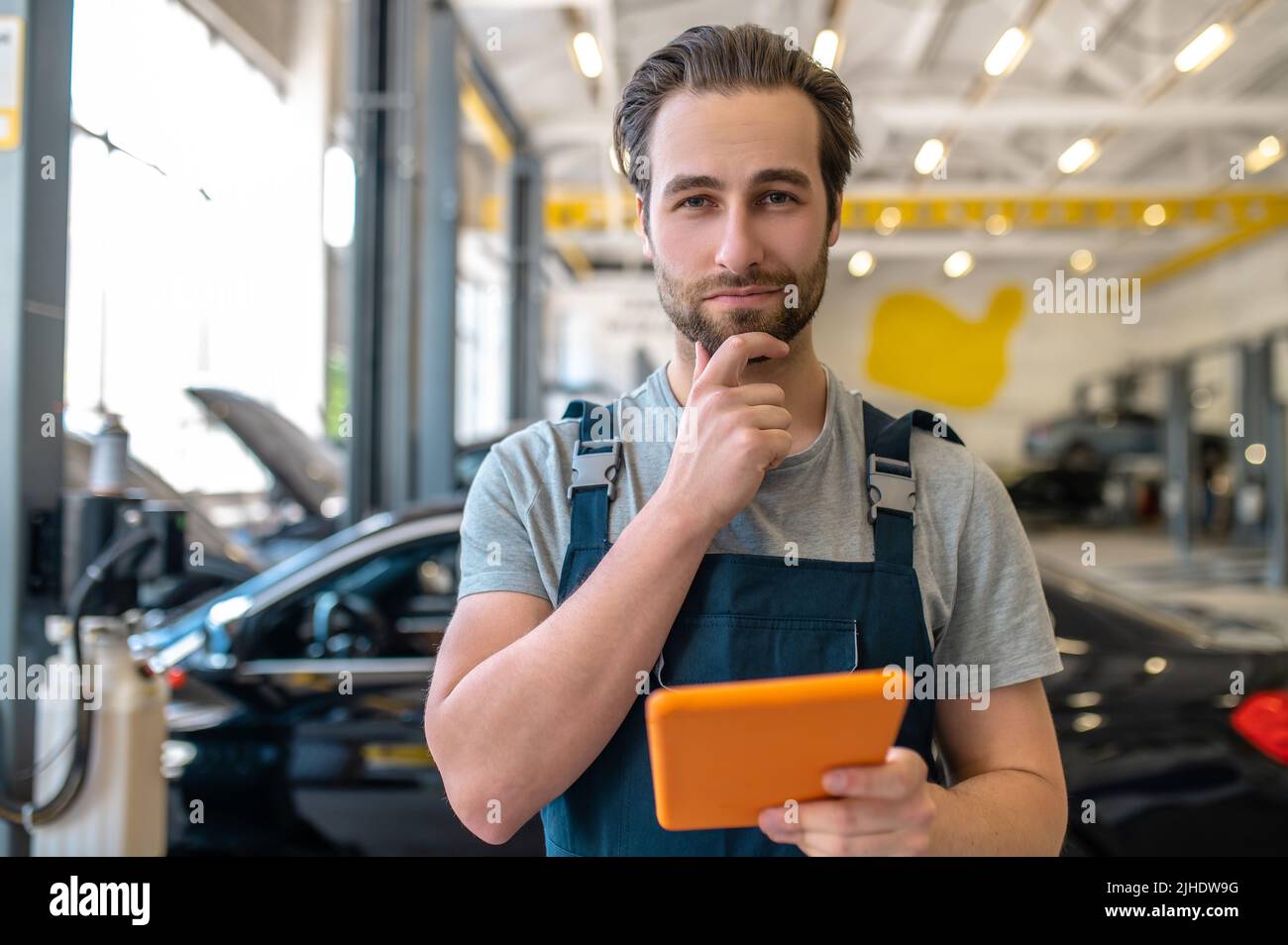 Uomo con tablet che guarda con sicurezza alla fotocamera Foto Stock
