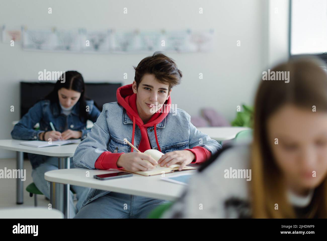 Gli studenti delle scuole superiori prestano attenzione in classe, seduti sulla scrivania e scrivendo appunti, tornano al concetto scolastico. Foto Stock