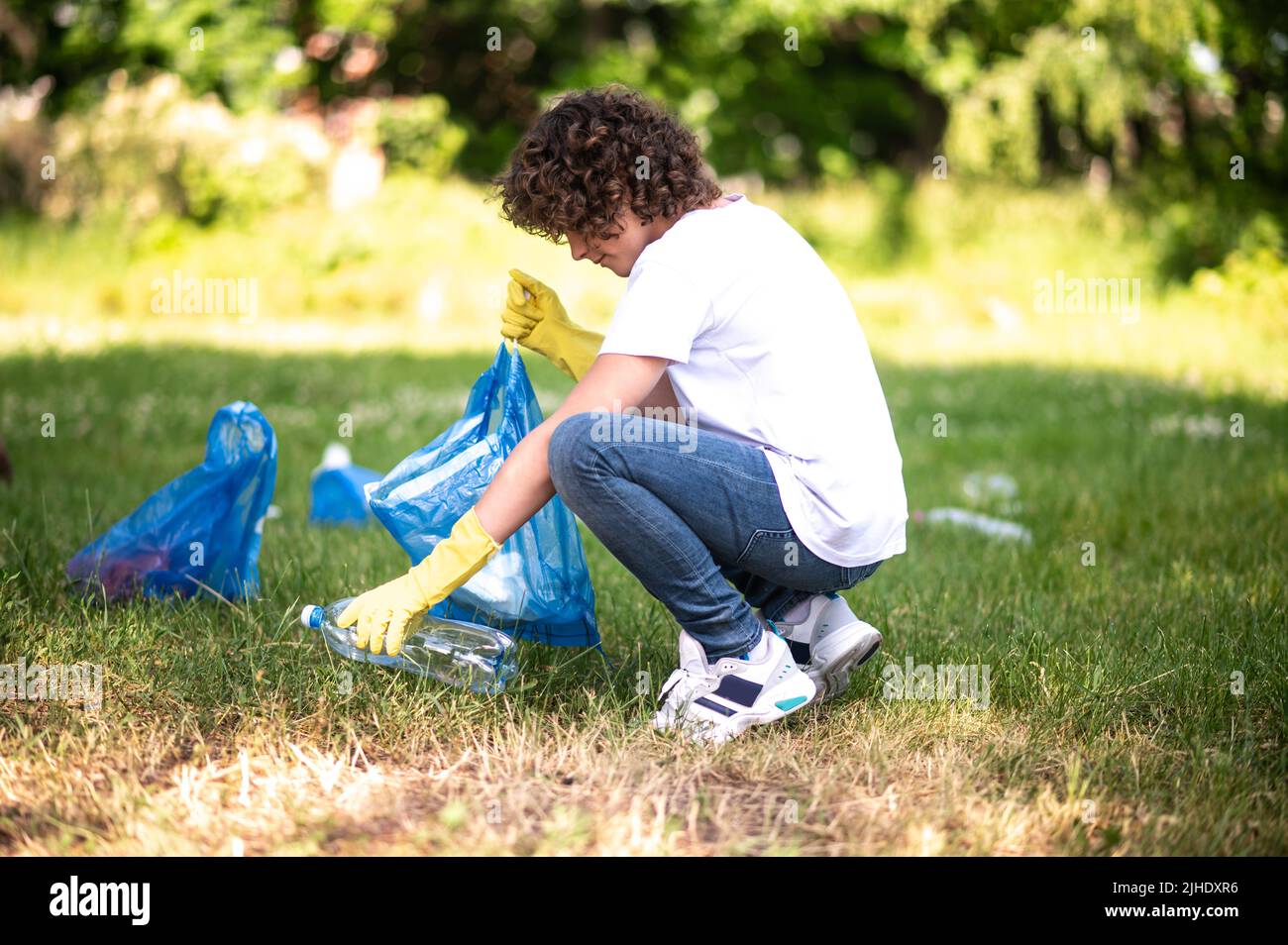 Giovane ragazzo che raccoglie e smistando rifiuti nel parco Foto Stock