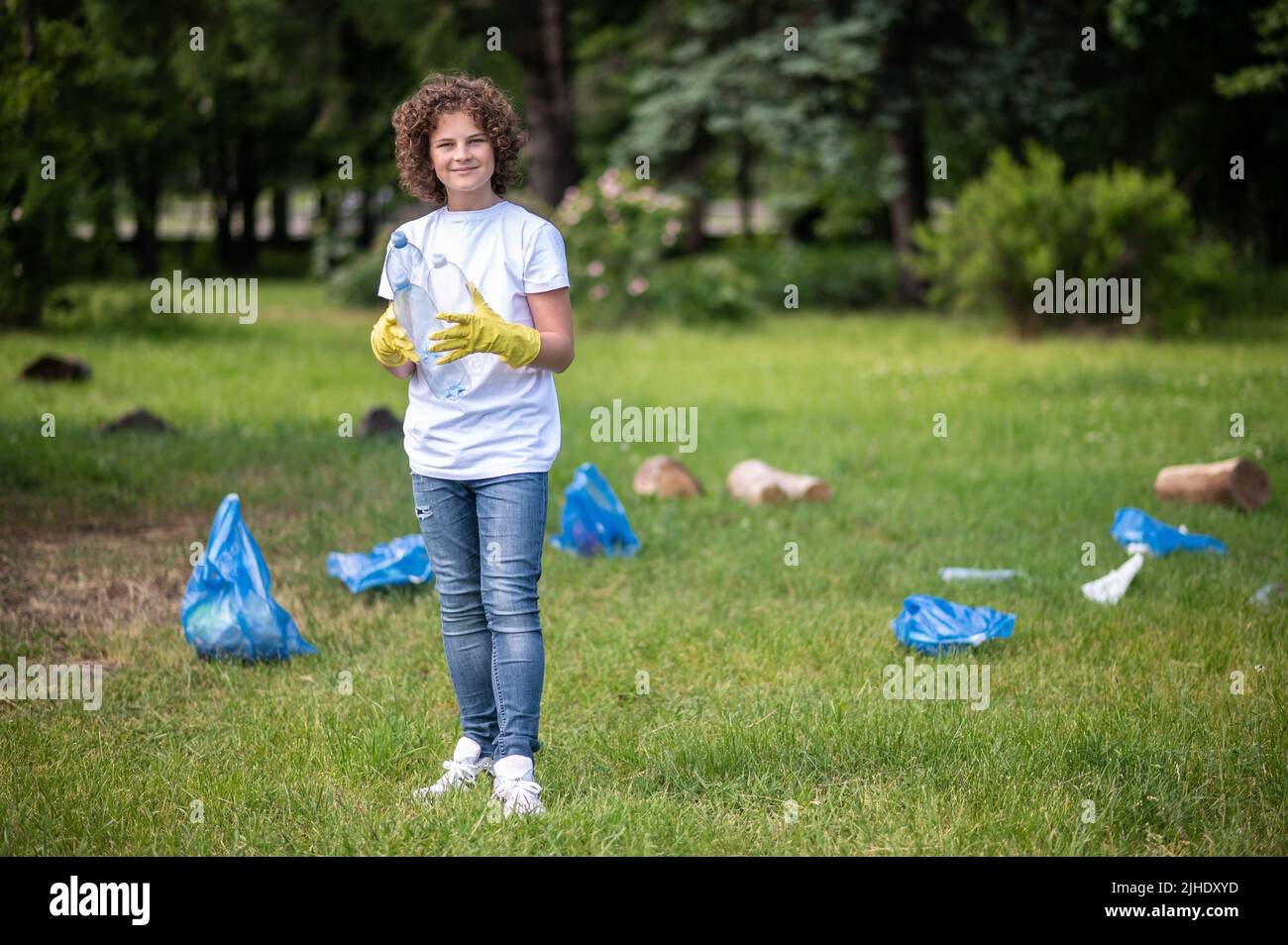 Bambino in guanti gialli nel parco raccolta rifiuti Foto Stock