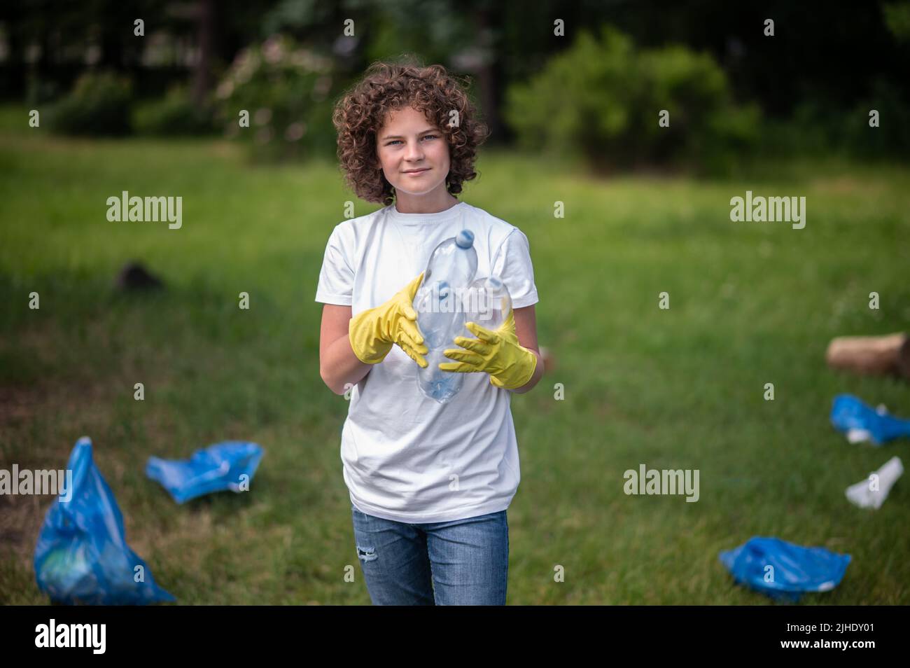 Bambino in guanti gialli nel parco raccolta rifiuti Foto Stock