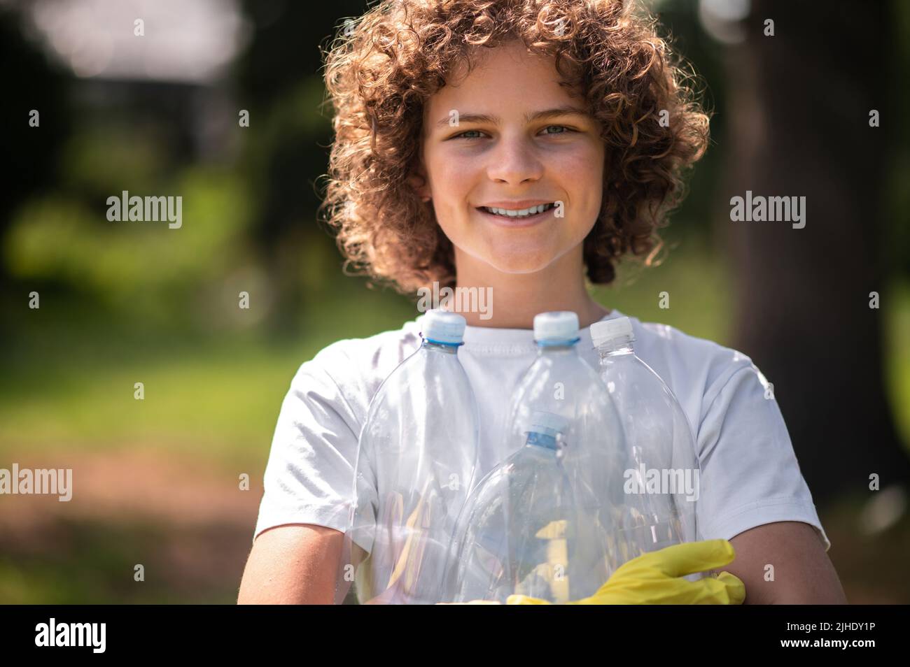 Giovani bottiglie di plastica gethering spontanee dai capelli ricci Foto Stock