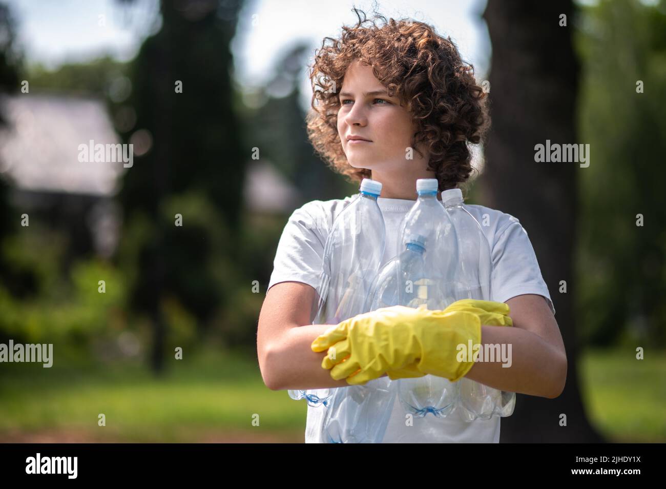 Giovani bottiglie di plastica gethering spontanee dai capelli ricci Foto Stock