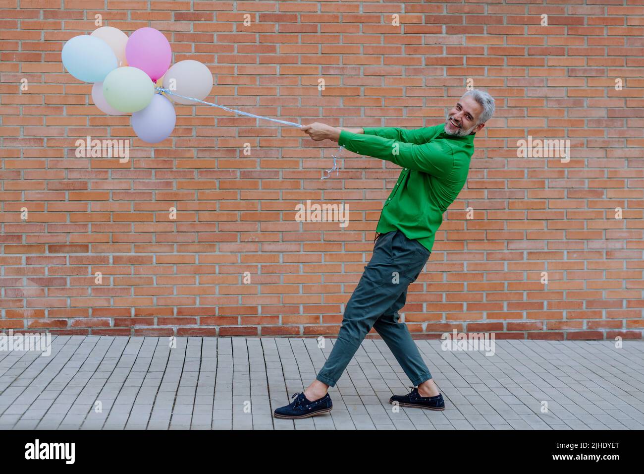 Ritratto divertente di felice energico uomo d'affari maturo tenendo palloncini in strada, sensazione di libertà, lavoro vita equilibrio concetto. Foto Stock