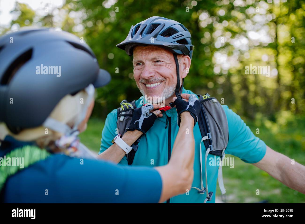 Attiva coppia senior in bicicletta al parco estivo, l'uomo sta indossando il casco, concetto di stile di vita sano. Foto Stock