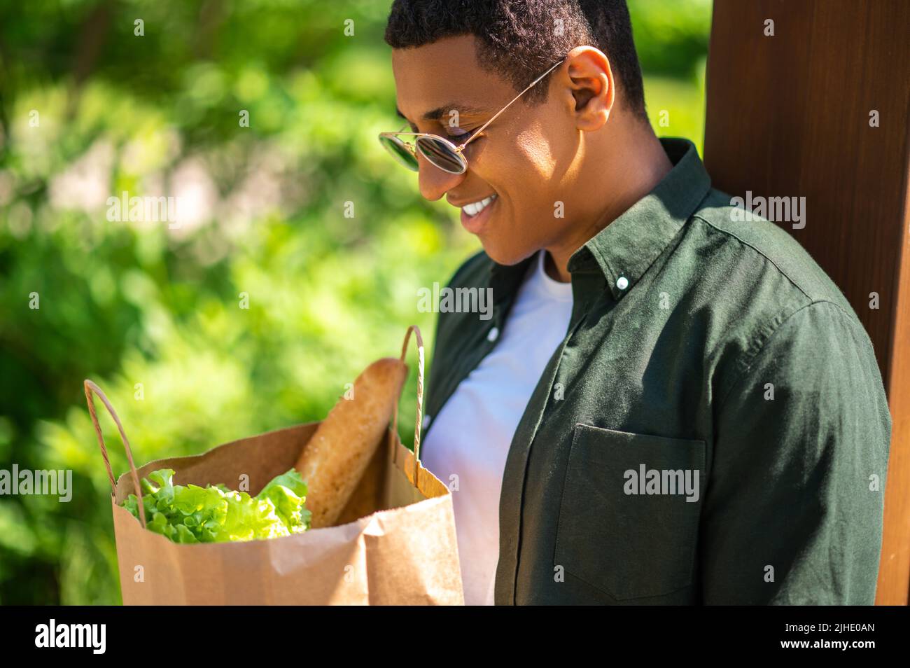 Uomo che guarda felice in sacchetto di cibo Foto Stock