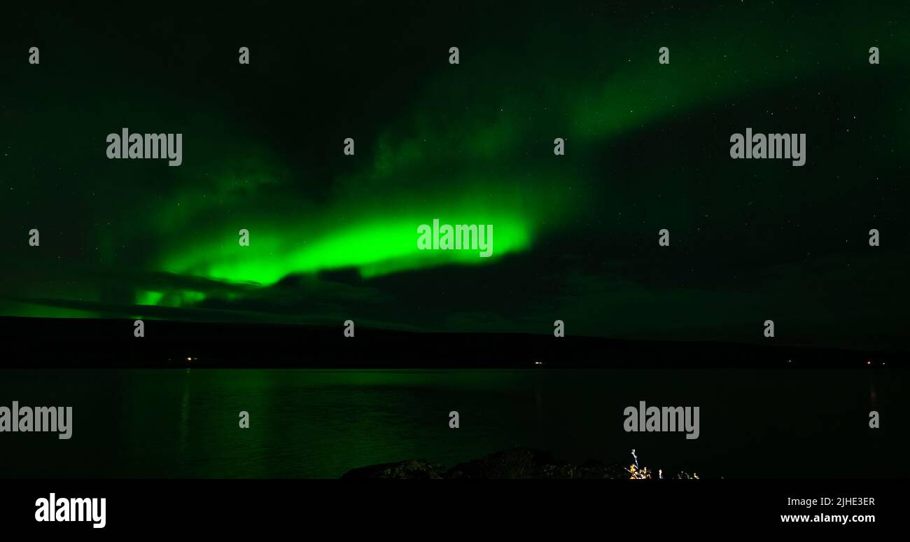 Aurora boreale sopra il lago di pianura con le luci della casa Foto Stock