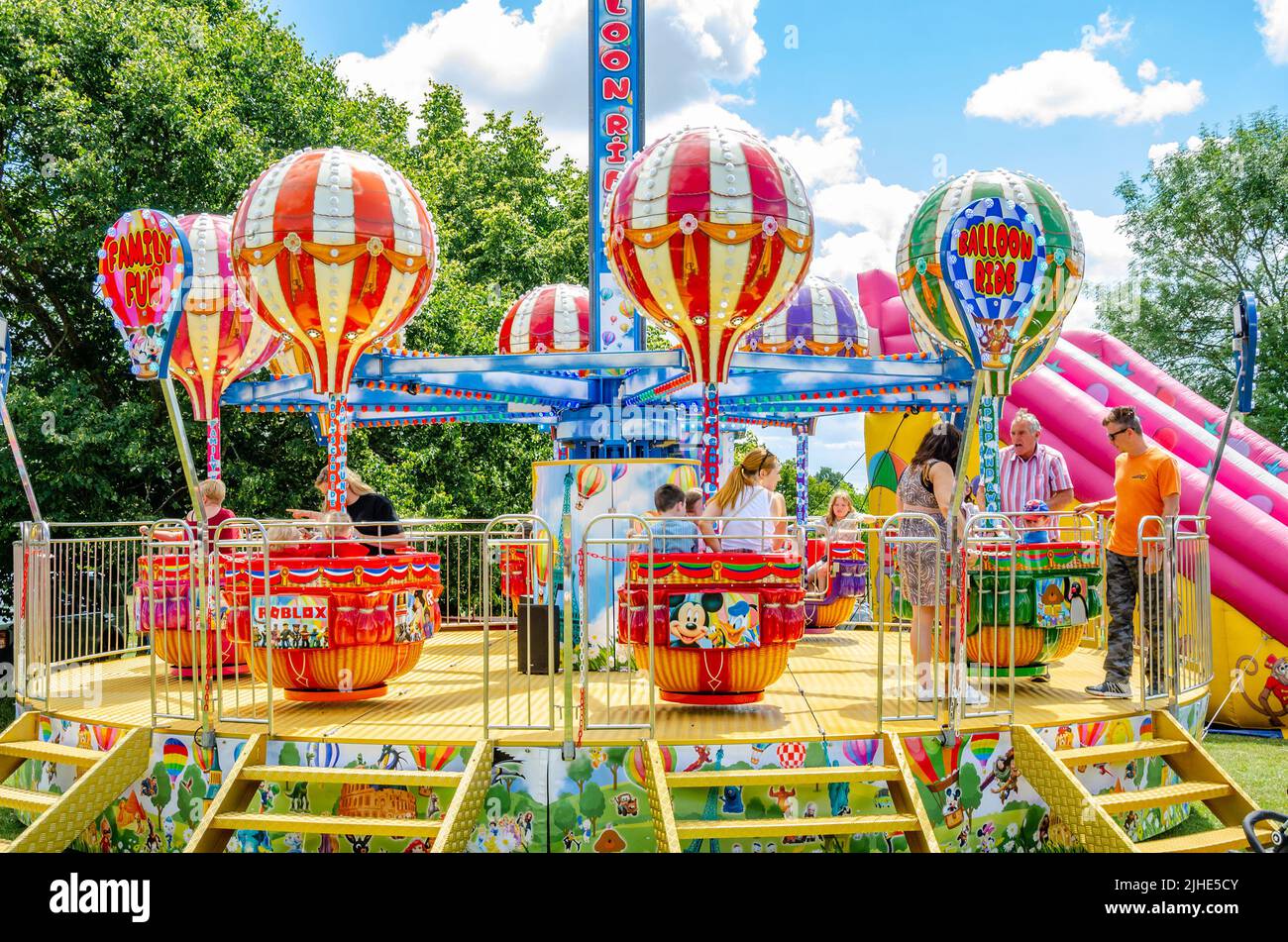 Un giro nella zona fieristica per bambini con carrozze con palloncini che girano e si alzano e cadono. Foto Stock