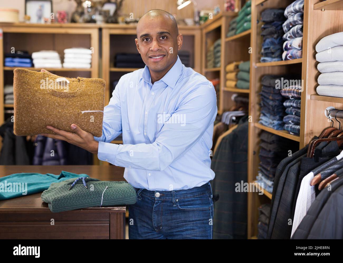 Venditore che offre giacca tuta in boutique maschile Foto Stock