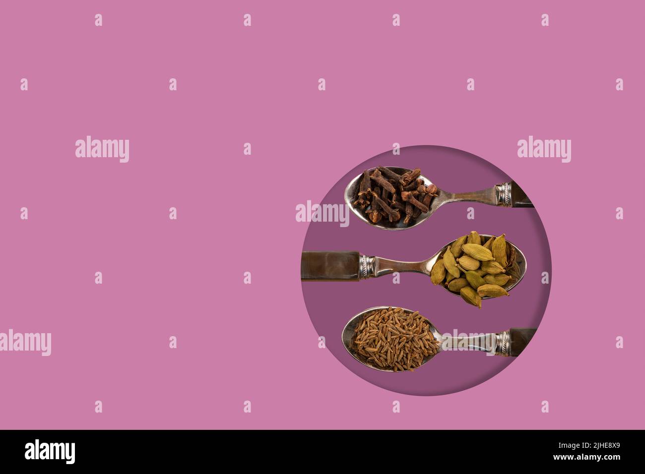 selezione di spezie indiane assortite semi di cumino cardamomo cialde di cardamone chiodi di garofano su cucchiai su un colorato sfondo rosa lavanda Foto Stock