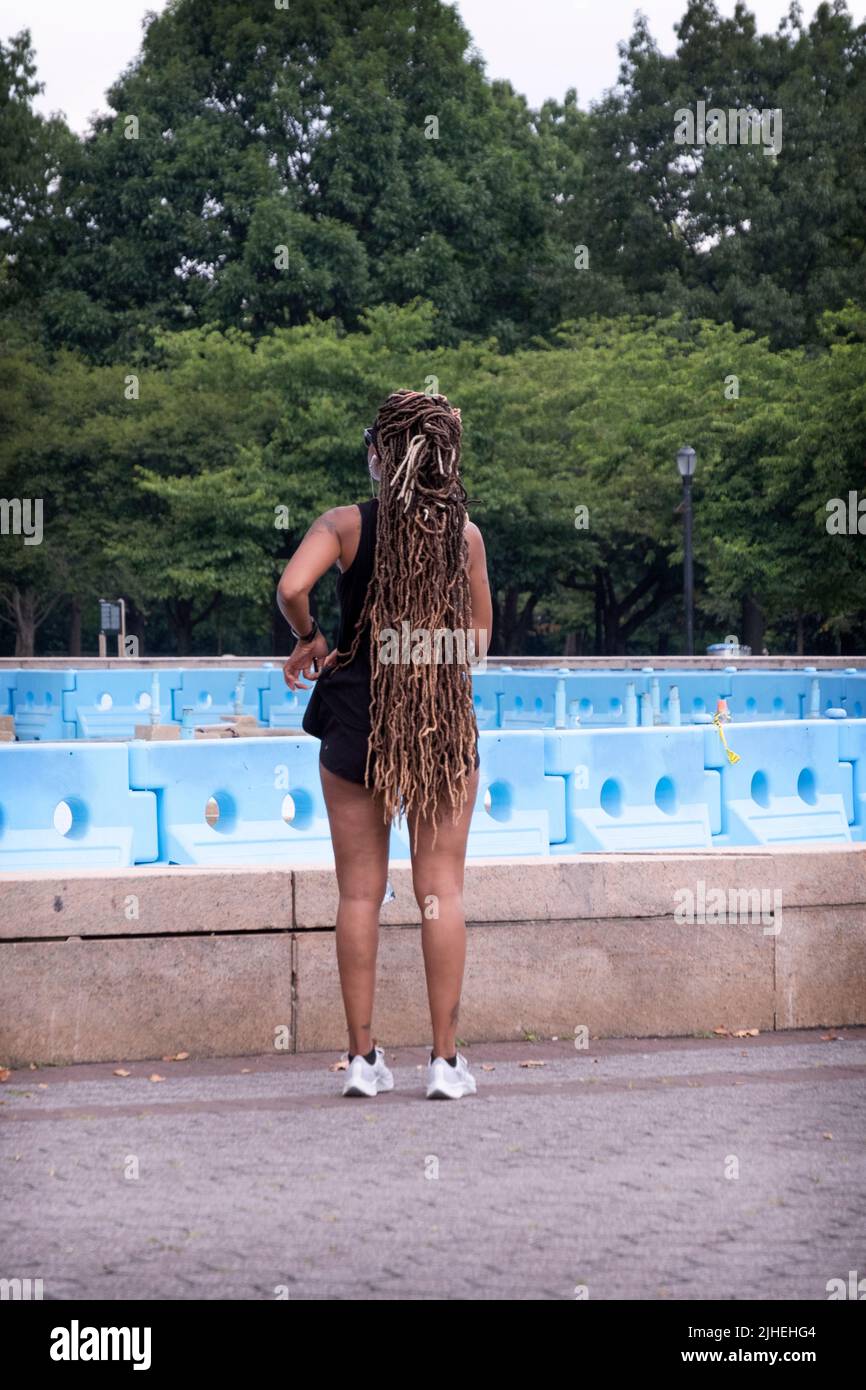 Donna vestita di abbigliamento sportivo e con prolunghe dei capelli molto lunghe. Da dietro. Al Flushing Meadows Corona Park a Queens, New York. Foto Stock