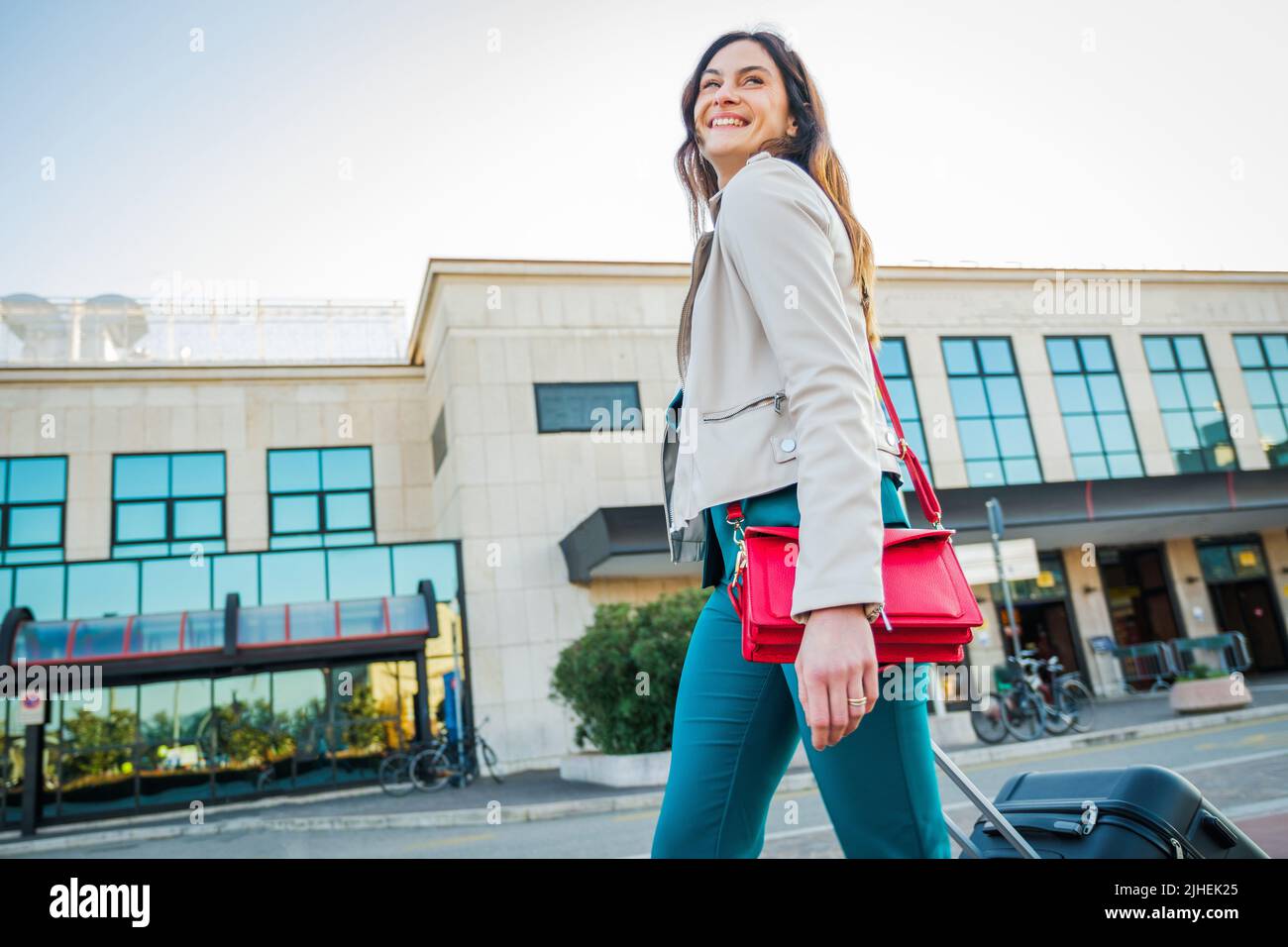 Ritratto di una donna in viaggio d'affari che cammina in una stazione ferroviaria o aeroporto andando al cancello d'imbarco con bagaglio a mano Foto Stock