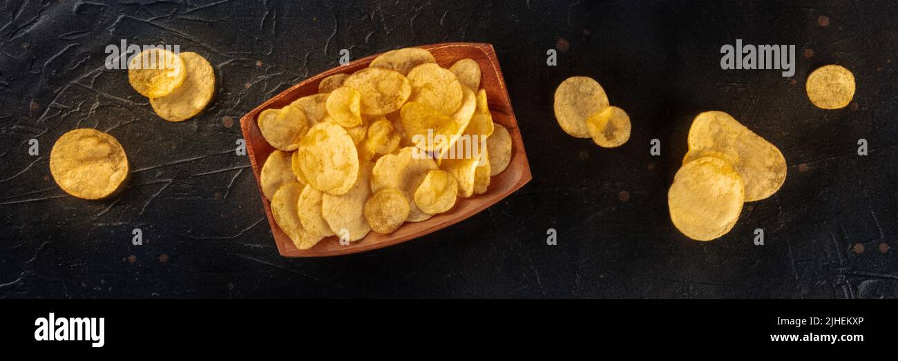 Patatine fritte o patatine fritte, uno spuntino salato, si stende il panorama su uno sfondo di ardesia nera Foto Stock