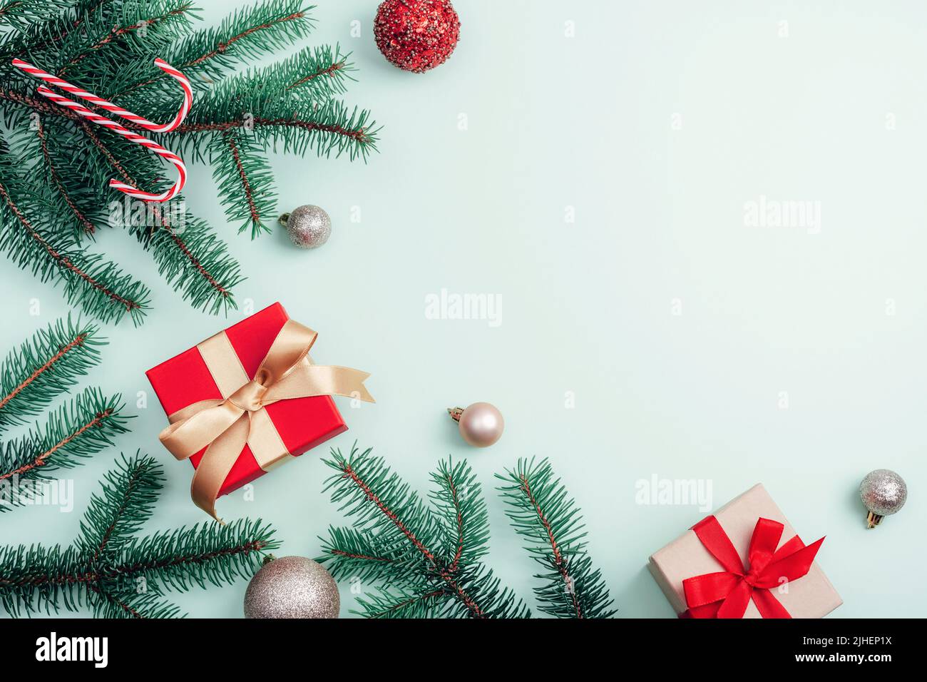 Decorazioni natalizie, scatole regalo, rami di abete, baubles e canna di caramella su sfondo verde chiaro. Vista dall'alto, disposizione piatta, spazio di copia. Foto Stock