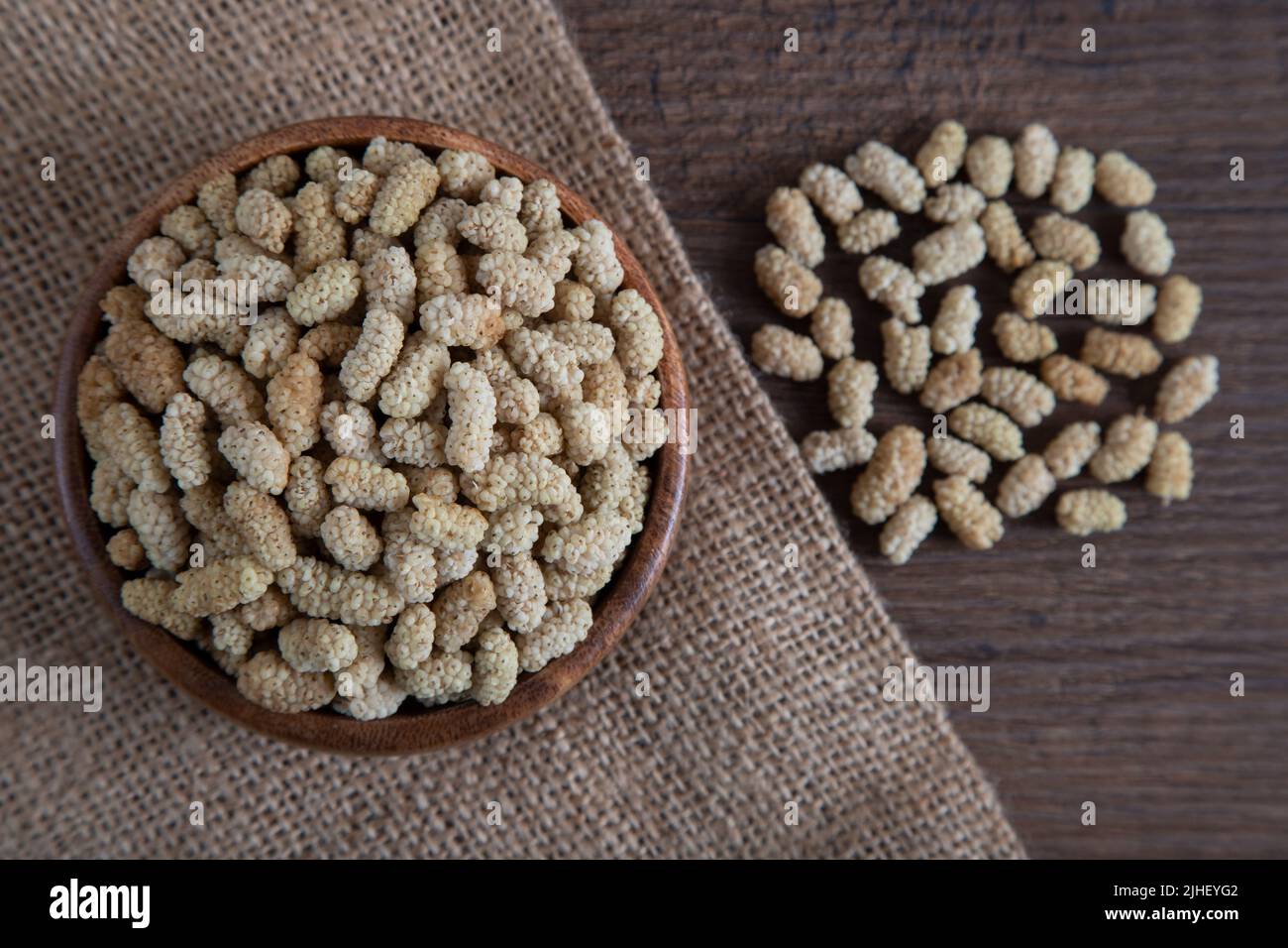 Ciotola piena di gelso secco su sfondo di legno Foto Stock