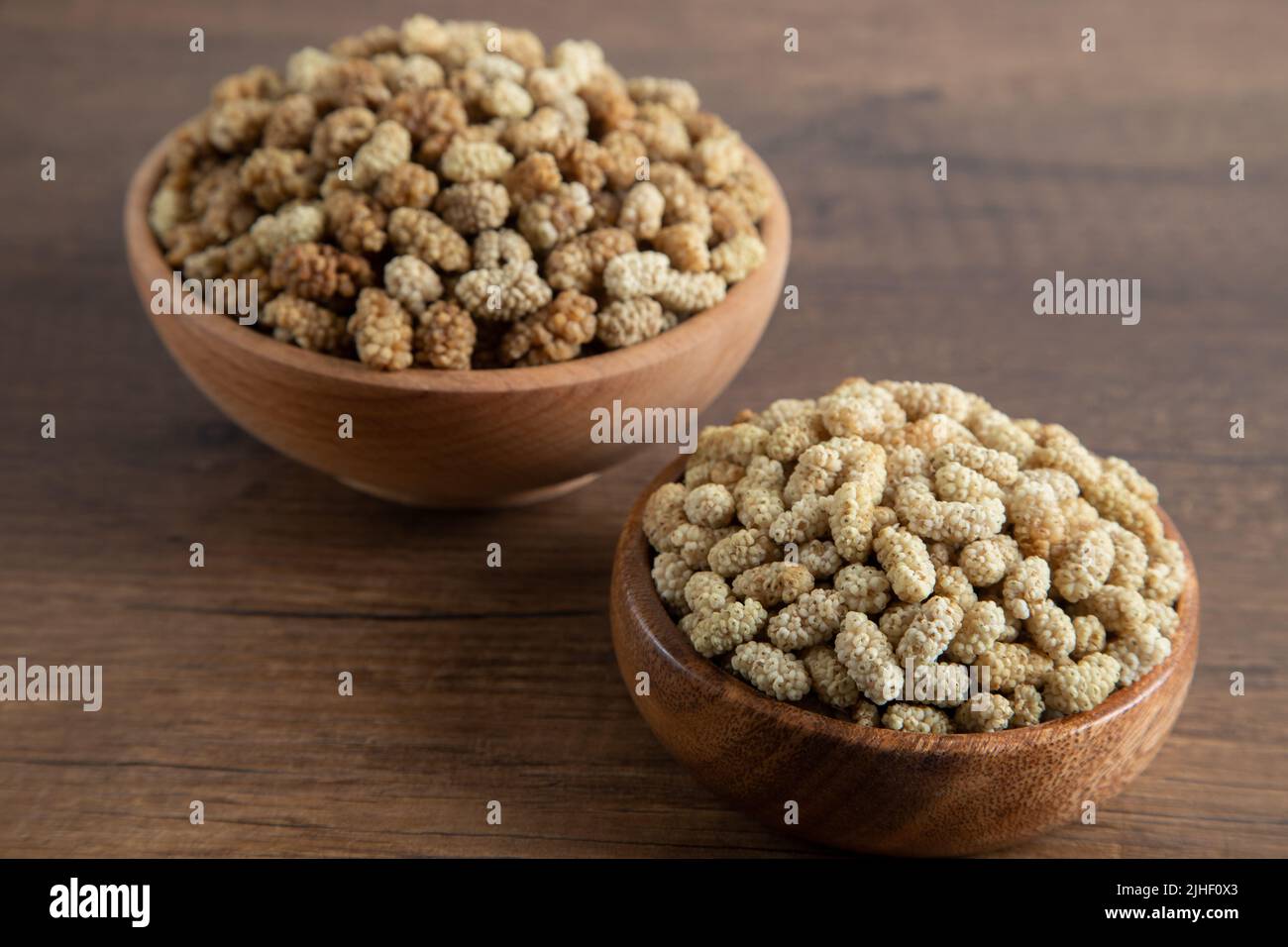 Ciotola piena di gelso secco su sfondo di legno Foto Stock
