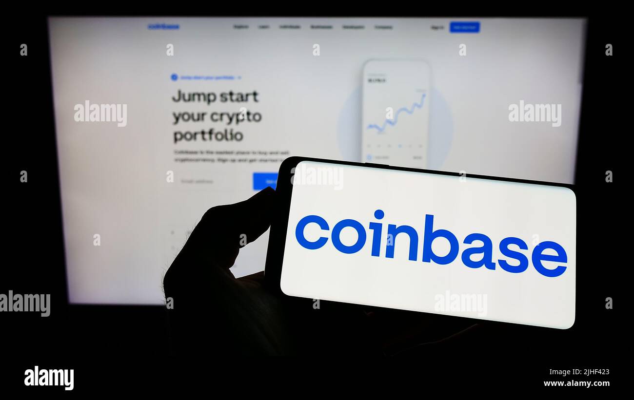 Persona che tiene il cellulare con il logo della società americana Crypto Exchange Coinbase Global Inc. Sullo schermo di fronte al sito web. Mettere a fuoco sul display del telefono. Foto Stock