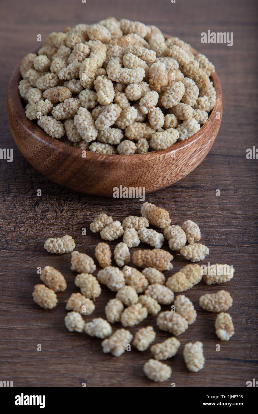 Ciotola piena di gelso secco su sfondo di legno Foto Stock
